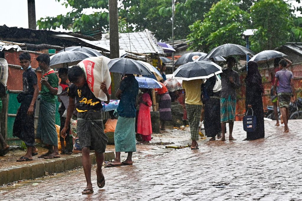 Pengungsi Rohingya menunggu bantuan di tempat distribusi makanan saat hujan monsun di kamp pengungsi Kutupalong di Ukhia, Bangladesh, Rabu (10/8/2022). 
