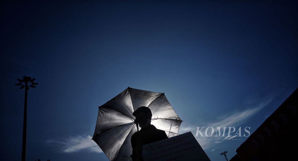 Siluet seorang aktivis dengan payungnya saat mengikuti Aksi Kamisan ke-767 di depan Istana Merdeka, Jakarta, Kamis (9/3/2023). Aksi Kamisan ke -767 ini mengangkat tema hak perlindungan perempuan seiring peringatan Hari Perempuan Internasional. 