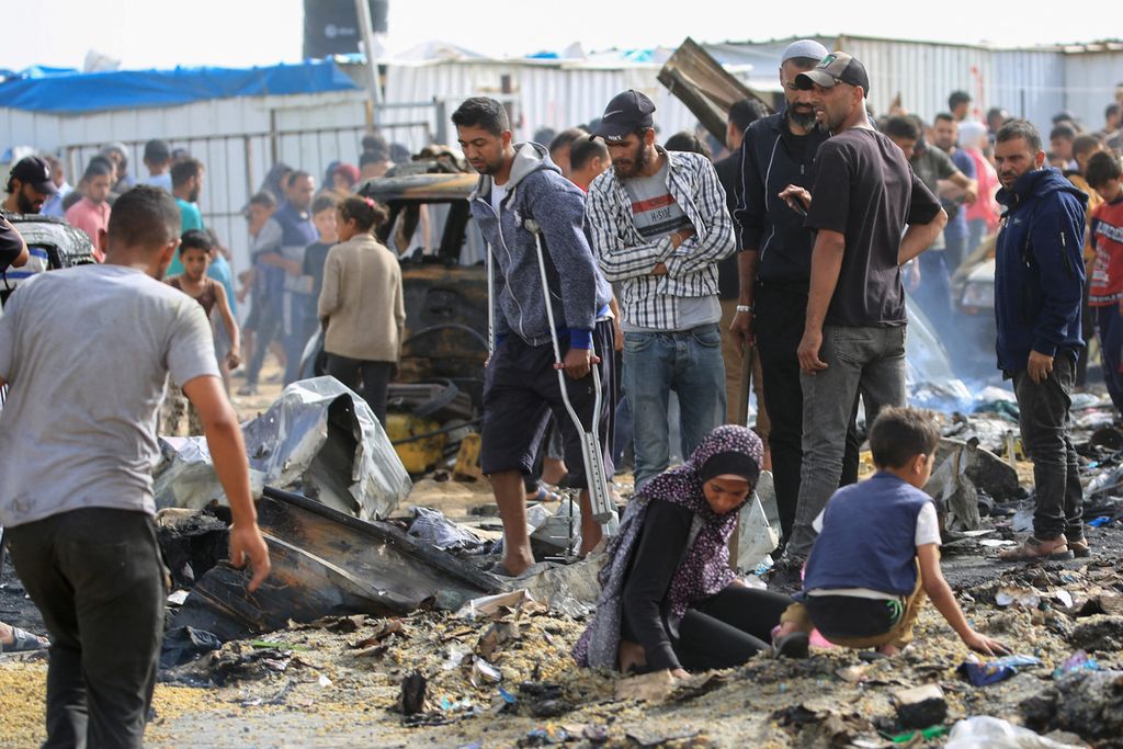 Warga Palestina mengais puing-puing seusai serangan udara Israel yang menyasar sebuah kamp pengungsi di Rafah pada 27 Mei 2024. Israel menyerang sebuah kamp pengungsi zona aman di Rafah di Gaza selatan. Serangan tersebut menewaskan sedikitnya 35 warga Palestina, banyak korbannya adalah perempuan dan anak-anak.  