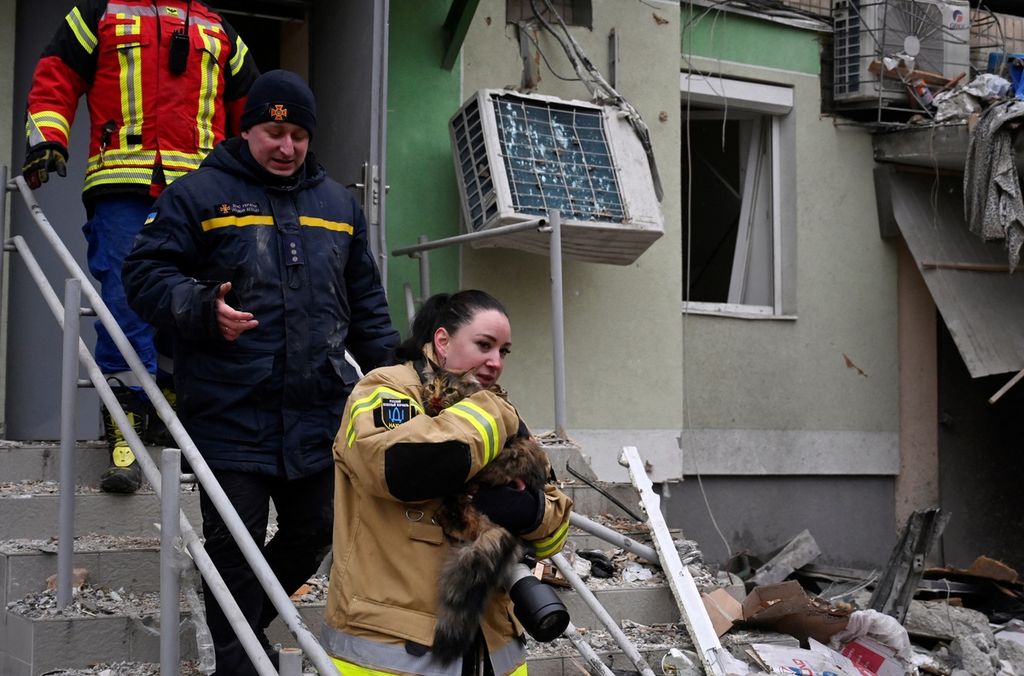 Petugas penyelamat membawa seekor kucing yang diselamatkan dari puing-puing bangunan tempat tinggal yang hancur setelah serangan rudal di Dnipro, Ukraina, Minggu (15/1/2023).