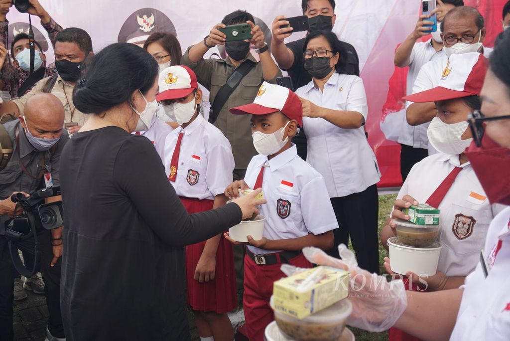 Ketua DPR Puan Maharani menyerahkan makanan tambahan berupa bubur ikan tuna, susu, dan bubur kacang hijau bagi siswa-siswa SD di Monumen Trikora di Pulau Lembeh, Kota Bitung, Sulawesi Utara, pada Rabu (9/2/2022).