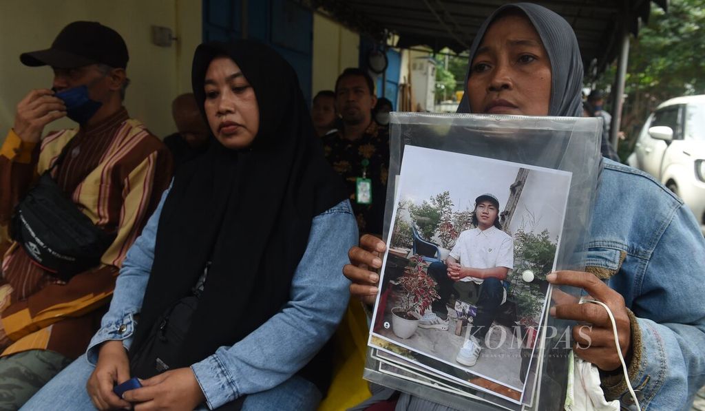 Rini Hanifah (43) memegang foto anaknya, Agus Rainsyah, yang menjadi korban dalam Tragedi Kanjuruhan dalam sidang perdana kasus Tragedi Kanjuruhan di Pengadilan Negeri Surabaya, Jawa Timur, Senin (16/1/2023). 