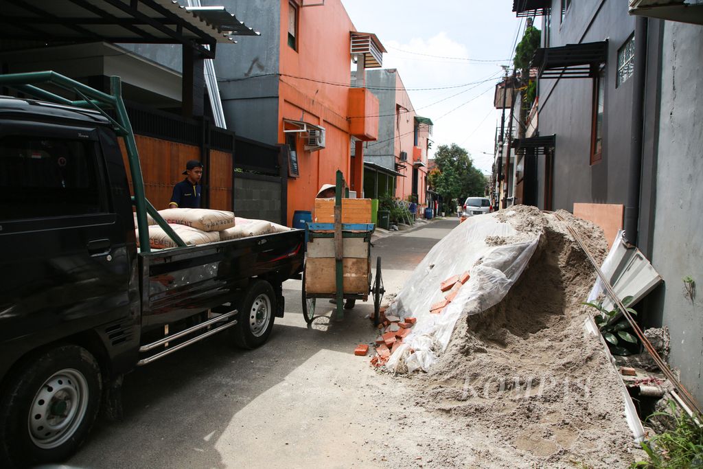 Material bangunan ditumpuk di pinggir jalan sehingga jalan menjadi sempit di Perumahan Pondok Pakulonan, Kecamatan Serpong Utara, Tangerang Selatan, Banten, Selasa (10/1/2023). 