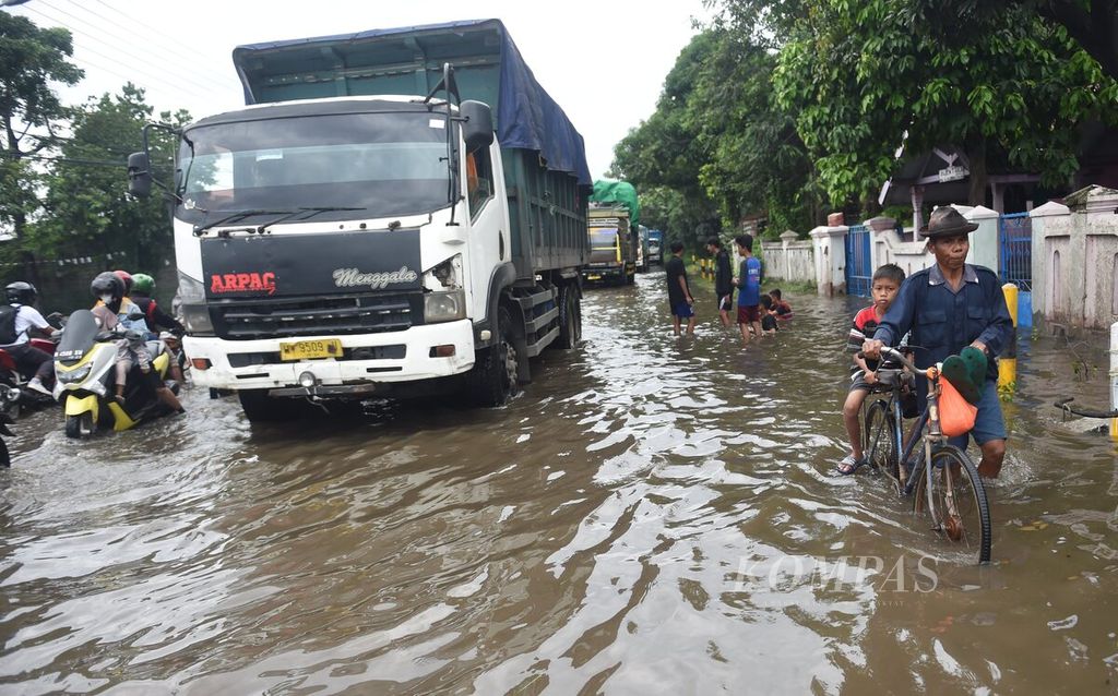 Warga melintas di Jalan Raya Surabaya-Banyuwangi yang terendam banjir di Kecamatan Rejoso, Kabupaten Pasuruan, Jatim, Minggu (12/2/2023).