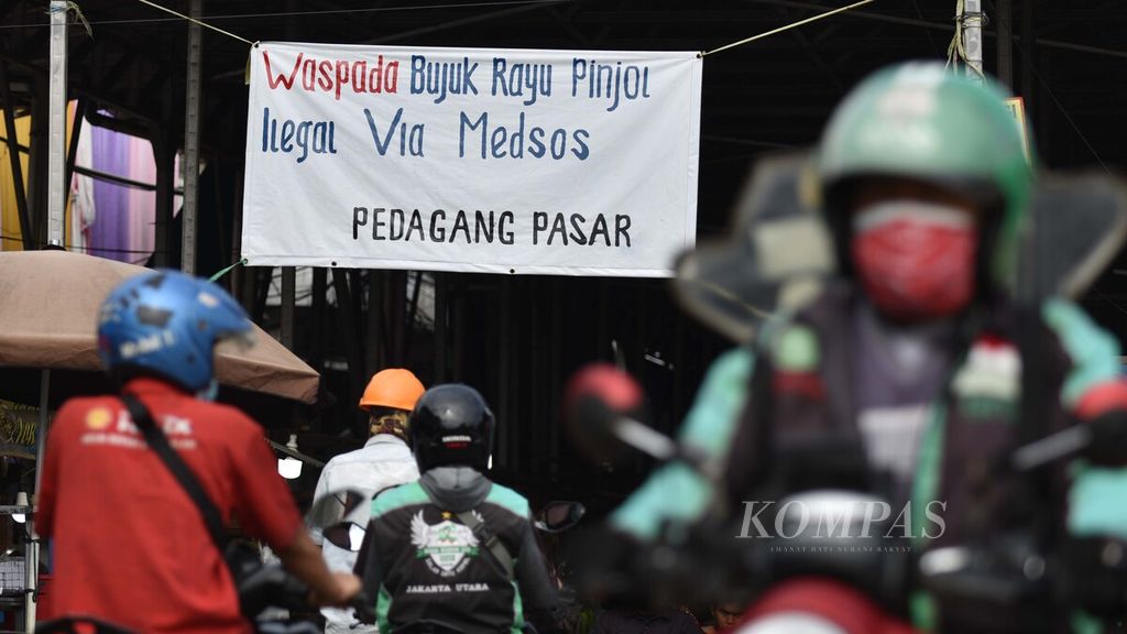 Spanduk ajakan untuk mewaspadai praktik pinjaman online (pinjol) ilegal menghiasi pintu masuk Pasar Muara Angke, Penjaringan, Jakarta Utara, Minggu (14/11/2021). 