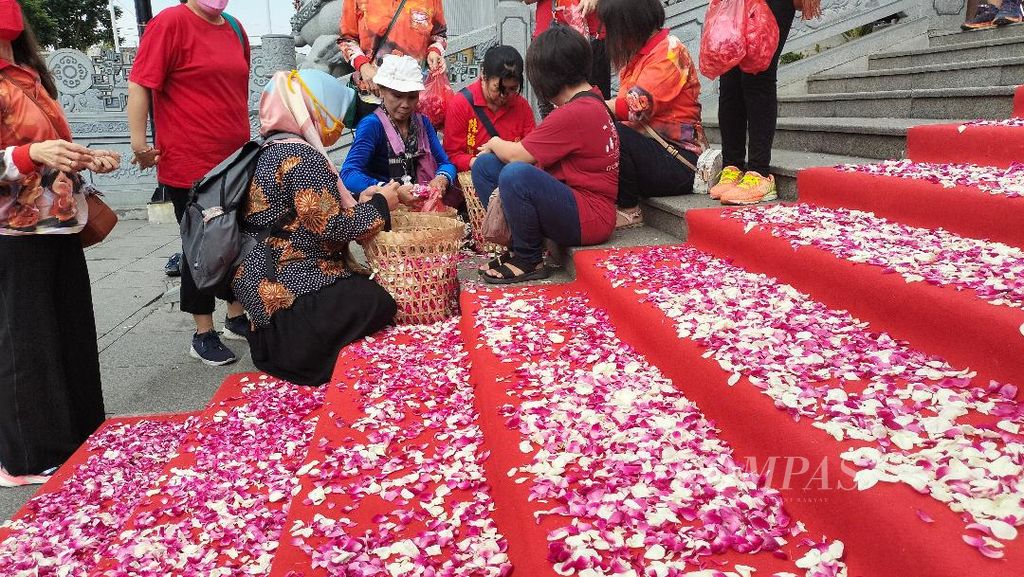 Tanpa diminta, seorang ibu berkerudung membantu menaburkan bunga di karpet merah yang akan dilewati rombongan biksu yang menjalankan ritual Thudong, di TITD Liong Hok Bio, Kota Magelang, Selasa (30/5/2023).