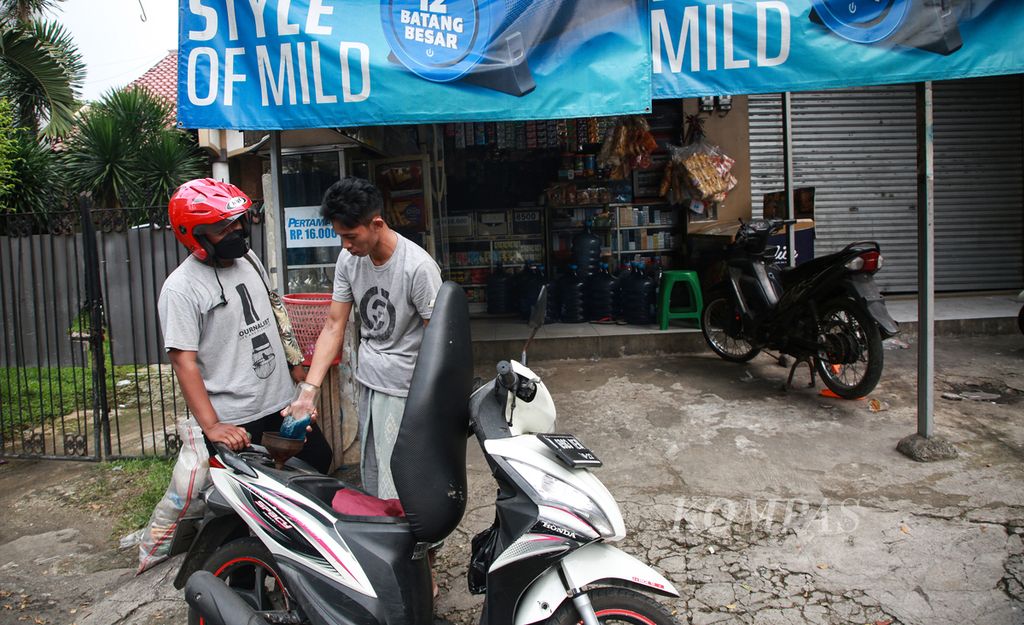 Herman, pengelola warung klontong madura di Jalan Tarumanegara, Ciputat Timur, Tangerang Selatan, sedang melayani pembelian bensin eceran, 