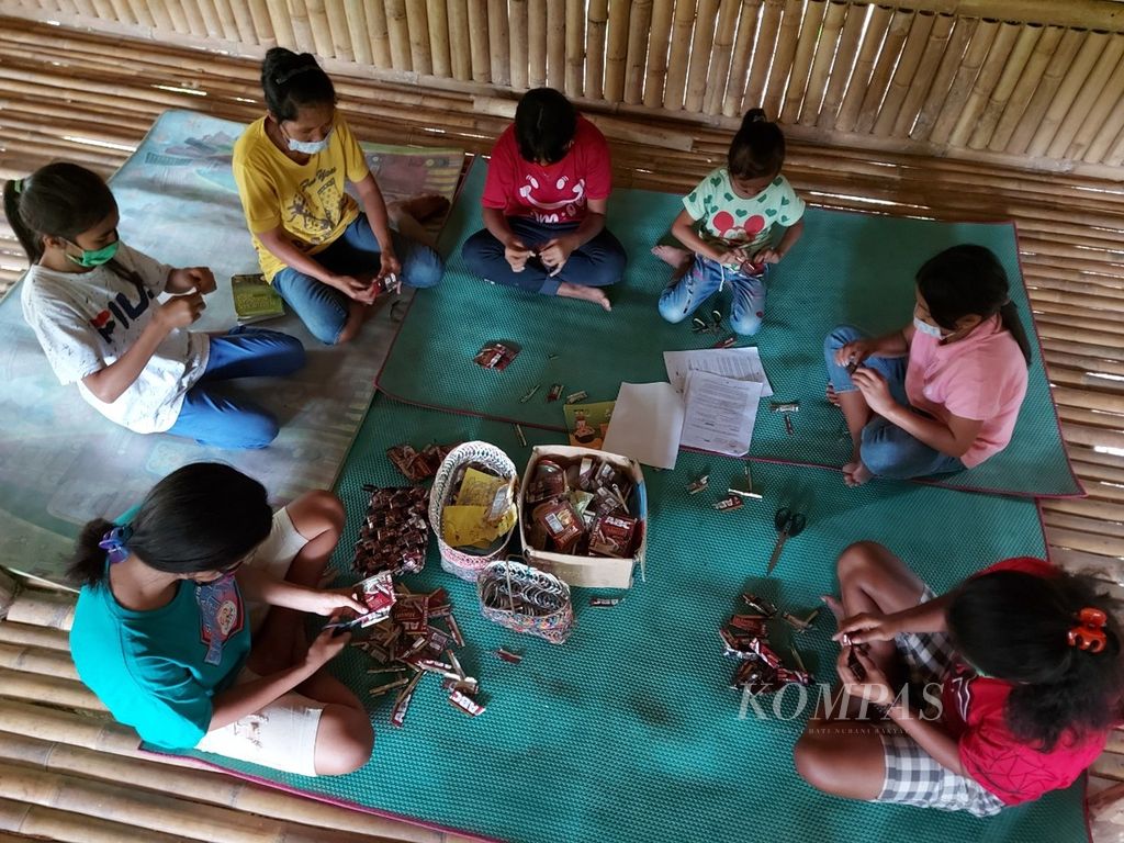 Anak-anak pekerja migran asal Sumba Barat Daya, NTT sedang merangkai wadah, dari sampah kemasan kopi pabrikan di <i>umma pande </i>atau rumah pintar di desa Welimbo Kecamatan Wejewa Timur, SBD. Dokumen Donders.