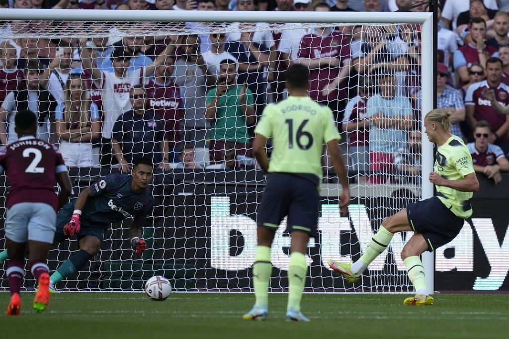 Pemain Manchester City Erling Haaland (kanan) mencetak gol pertama bagi timnya dari titik penalti saat kiper West Ham Alphonse Areola gagal menahannya, pada laga pekan pertama Liga Inggris di Stadion London, London, Senin (8/8/2022) dini hari WIB. City menang 2-0 pada laga itu. 