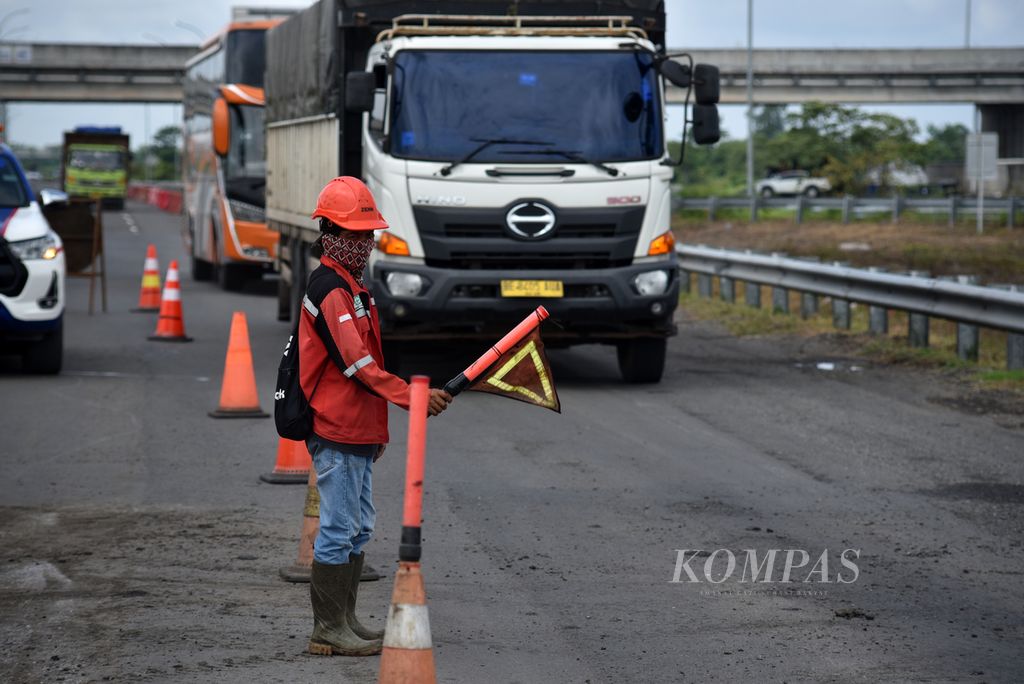 Petugas mengatur kecepatan kendaraan saat melintasi kawasan proyek perbaikan jalan di Tol Kayu Agung-Palembang, Sumatera Selatan, Rabu (27/3/2024). Waskita Sriwijaya Tol bersinergi dan berkoordinasi dengan pihak kepolisian dan pihak-pihak terkait lainnya untuk memastikan kenyamanan para pemudik.