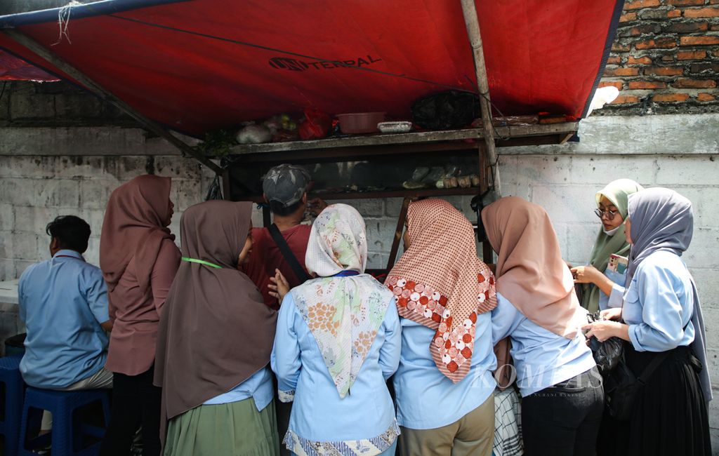Para buruh membeli makanan dari pedagang di luar area pabrik saat jam makan siang di kawasan Karawaci, Kota Tangerang, Banten, Rabu (22/11/2023).