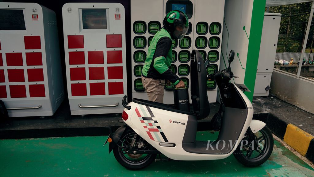 Ojek daring Gojek menukar baterai motor listrik Gogoro di <i>swapping station</i> di SPBU Pertamina, Jalan MT Haryono, Jakarta Selatan, Kamis (24/2/2022). Electrum, perusahaan patungan Gojek dan TBS Energi Utama, bersama Pertamina, Gogoro, dan Gesits bersinergi untuk mengakselerasi pengembangan ekosistem kendaraan listrik terintegrasi dan terlengkap di Indonesia.