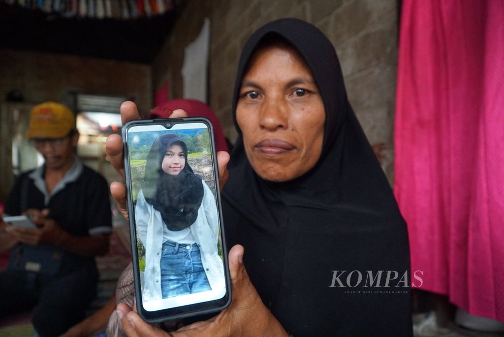 Eli Marlina (44), ibu almarhum Nia Kurnia Sari (18), memegang foto putri keduanya dari empat bersaudara itu, di Korong Pasa Surau, Nagari Guguak, Kecamatan 2 x 11 Kayu Tanam, Kabupaten Padang Pariaman, Sumatera Barat, Kamis (12/9/2024).