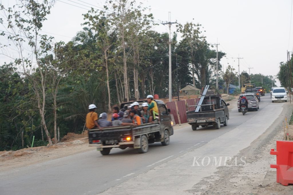 Para pekerja dalam proyek pembangunan Ibu Kota Nusantara melintasi jalan di Kecamatan Sepaku, Penajam Pser Utara, Kalimantan Timur, Jumat (22/9/2023) sore.