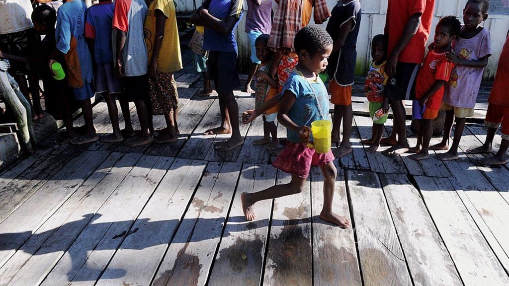 Anak-anak mengantre untuk mendapatkan bubur kacang hijau yang disediakan sukarelawan di Kampung Kapi, Distrik Pulau Tiga, Kabupaten Asmat, Papua, Senin (22/1).