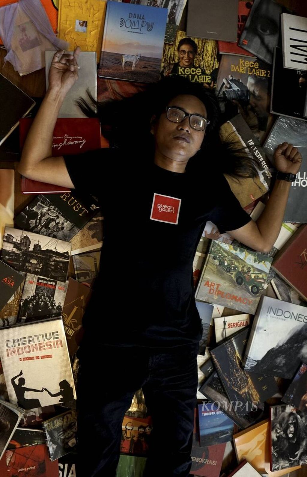 Andi Ari Setiadi di atas tumpukan buku-buku foto karyanya di Gueari Galeri di Pasar Alam, Perumahan Vida, Bekasi, Rabu (13/4/2022). 