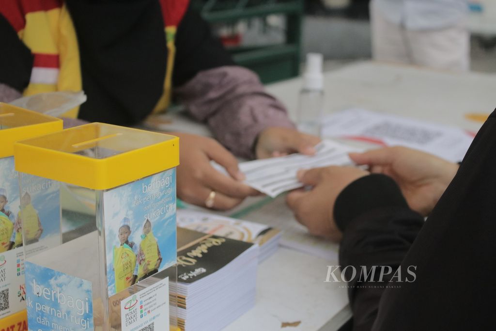 Petugas memberikan tanda bukti pembayaran zakat kepada warga di pos pelayanan Zakat Drive Thru dari Pusat Zakat Umat (PZU), Jalan Perintis Kemerdekaan, Kota Bandung, Jawa Barat, Selasa (11/5/2021).
