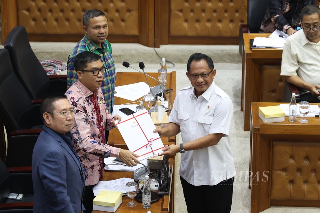 Menteri Dalam Negeri Tito Karnavian (kanan) menyerahkan pandangan pemerintan terkait revisi Rancangan Undang-Undang (RUU) Pilkada kepada Wakil Ketua Badan Legislasi Achmad Baidowi (tengah) disaksikan Wakil Ketua Baleg Abdul Wahid (dua dari kanan) dan Ketua Baleg Wihadi Wiyanto (kiri) di Kompleks Parlemen, Senayan Jakarta, Rabu (21/8/2024). 