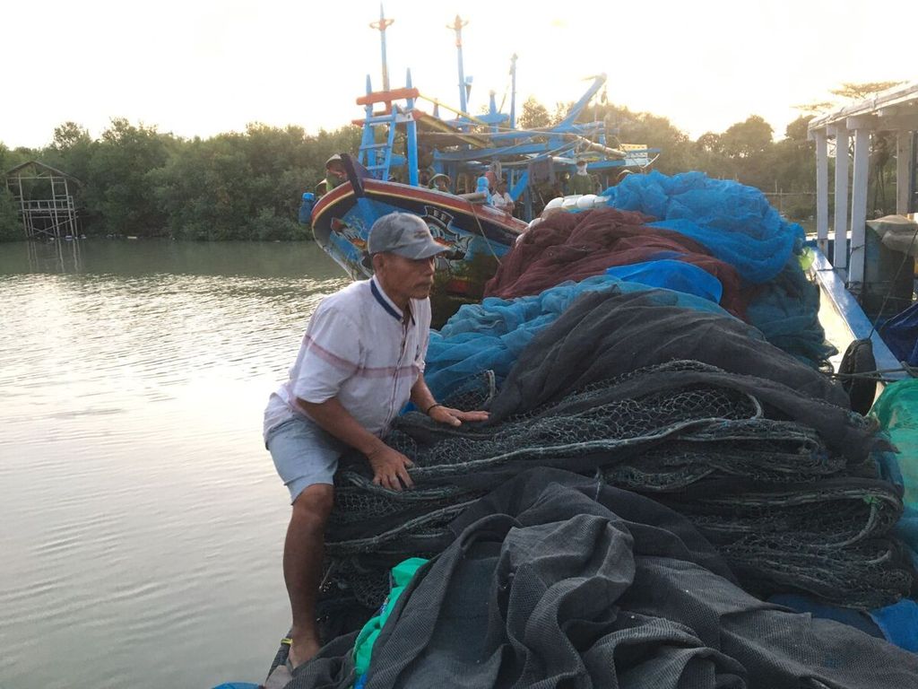 Dahuri (55), nelayan asal Desa Gebangmekar, Gebang, Cirebon, Jawa Barat, saat merapikan jaring di dermaga Gebang, Minggu (30/7/2023).