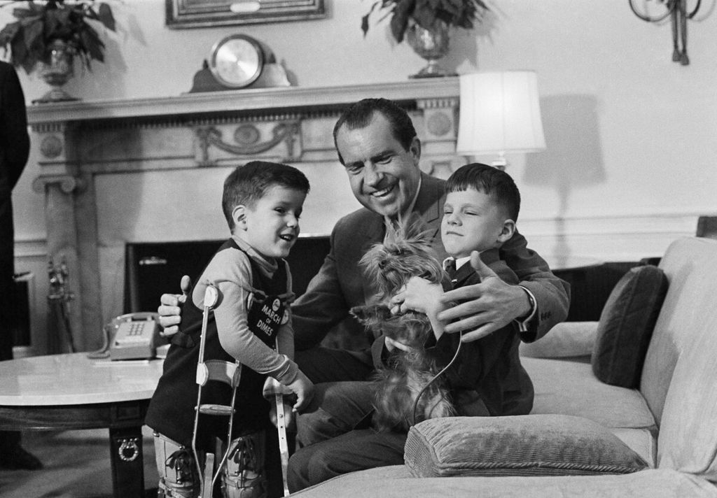 Presiden AS Richard Nixon tersenyum saat memamerkan salah satu hewan peliharaan Gedung Putih, seekor yorkshire terrier, Pasha, kepada dua pengunjung yunior di kantornya di Washington, AS, Kamis (5/2/1969).