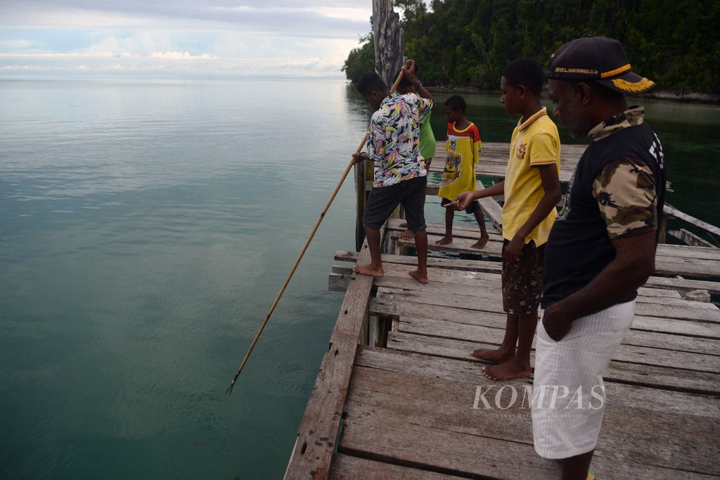 Warga mencari ikan dengan menggunakan tombak di dermaga Kampung Yensner, Teluk Mayalibit, Raja Ampat, Papua Barat, Kamis (3/6/2021).