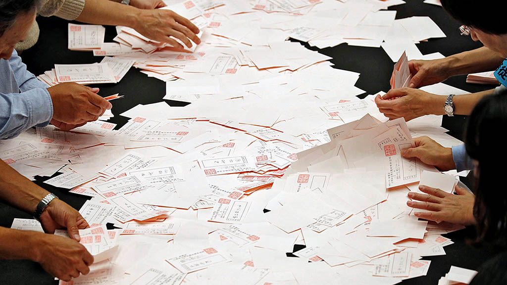 Petugas   pemungutan suara menghitung surat suara seusai berlangsungnya pemungutan suara untuk memilih anggota Majelis Rendah Jepang di sebuah tempat pemungutan suara di Tokyo, Jepang, Minggu (22/10). 