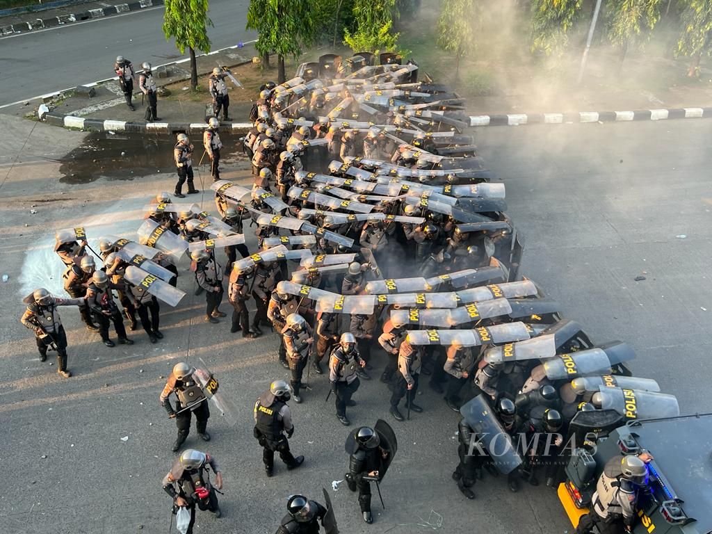 Polisi melindungi diri dengan tameng untuk menghindari lemparan batu dari arah mahasiswa dalam aksi unjuk rasa di Makassar, Senin (11/4/2022).