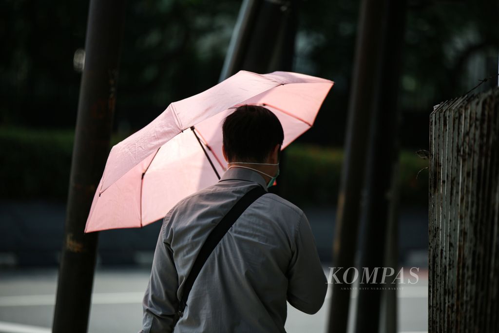 Warga menggunakan payung untuk menghindari terik matahari di kawasan Menteng, Jakarta Pusat, Selasa (23/5/2023). Badan Meteorologi, Klimatologi, dan Geofisika (BMKG) menjelaskan bahwa suhu panas yang terjadi sekarang merupakan fenomena akibat adanya gerak semu matahari. Ini menjadi siklus yang biasa dan terjadi setiap tahun.