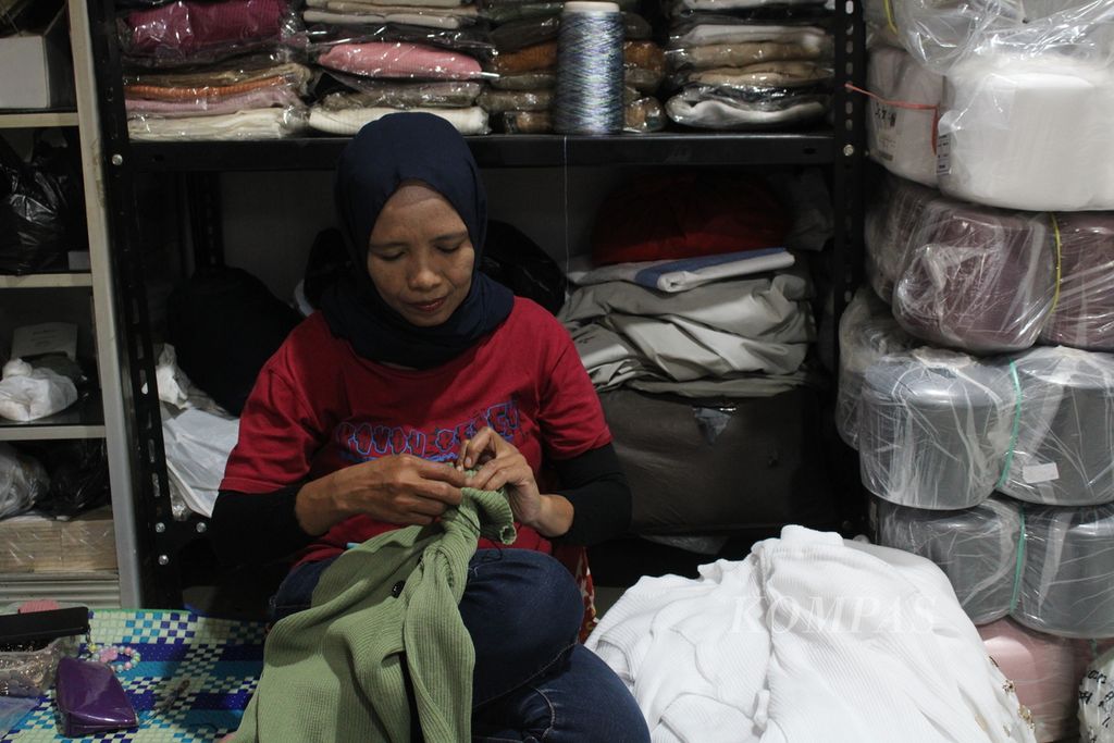 Salah satu pekerja di rumah produksi pakaian rajut di Kampoeng Radjoet, Kecamatan Batununggal, Kota Bandung, Jawa Barat, merapikan benang dari pakaian sebelum dikemas, Rabu (28/2/2024).