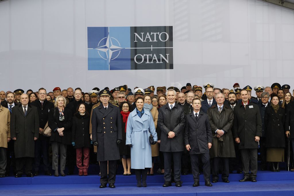 Di barisan depan, Sekjen NATO Jens Stoltenberg, diapit Perdana Menteri Swedia Ulf Kristersson (kanan) dan Putri Mahkota Kerajaan Swedia Victoria (kiri, berjaket biru muda), saat menyaksikan penaikan bendera Swedia di markas NATO di Brussels, Belgia, Senin (11/3/2024).