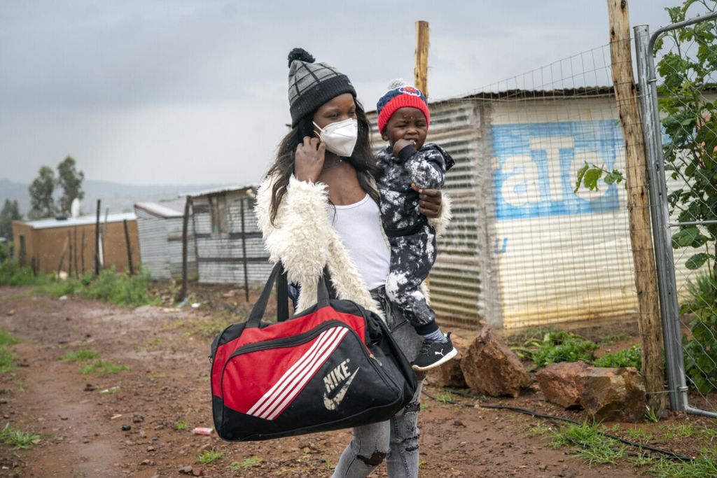 Takalane Mulaudzi (29) menggendong putranya, Dembe (2) di kampung kumuh Vlakfontein, Johannesburg, Afrika Selatan pada hari Senin (13/12/2021). Mereka hendak ke Rumah Sakit Baragwanath Soweto untuk mendapatkan vaksin Covid-19.    