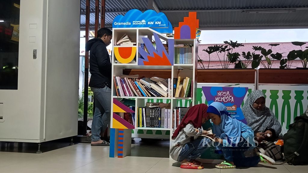 Seorang ibu duduk menemani dua anaknya membaca buku bergambar di Stasiun Besar Bogor, Kota Bogor, Jawa Barat, Sabtu (2/3/2024).