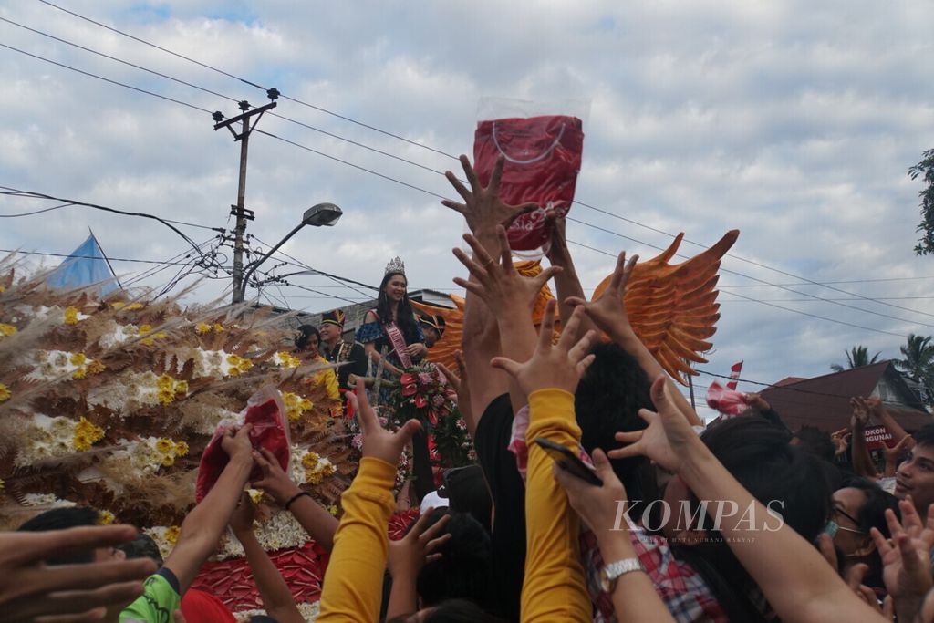 Warga Tomohon berebut kaus Wonderful Indonesia yang dilemparkan Putri Pariwisata 2018 Gabriella Patricia Mandolang dalam parade Tomohon International Flower Festival, Kamis (8/8/2019), di Tomohon, Sulawesi Utara.