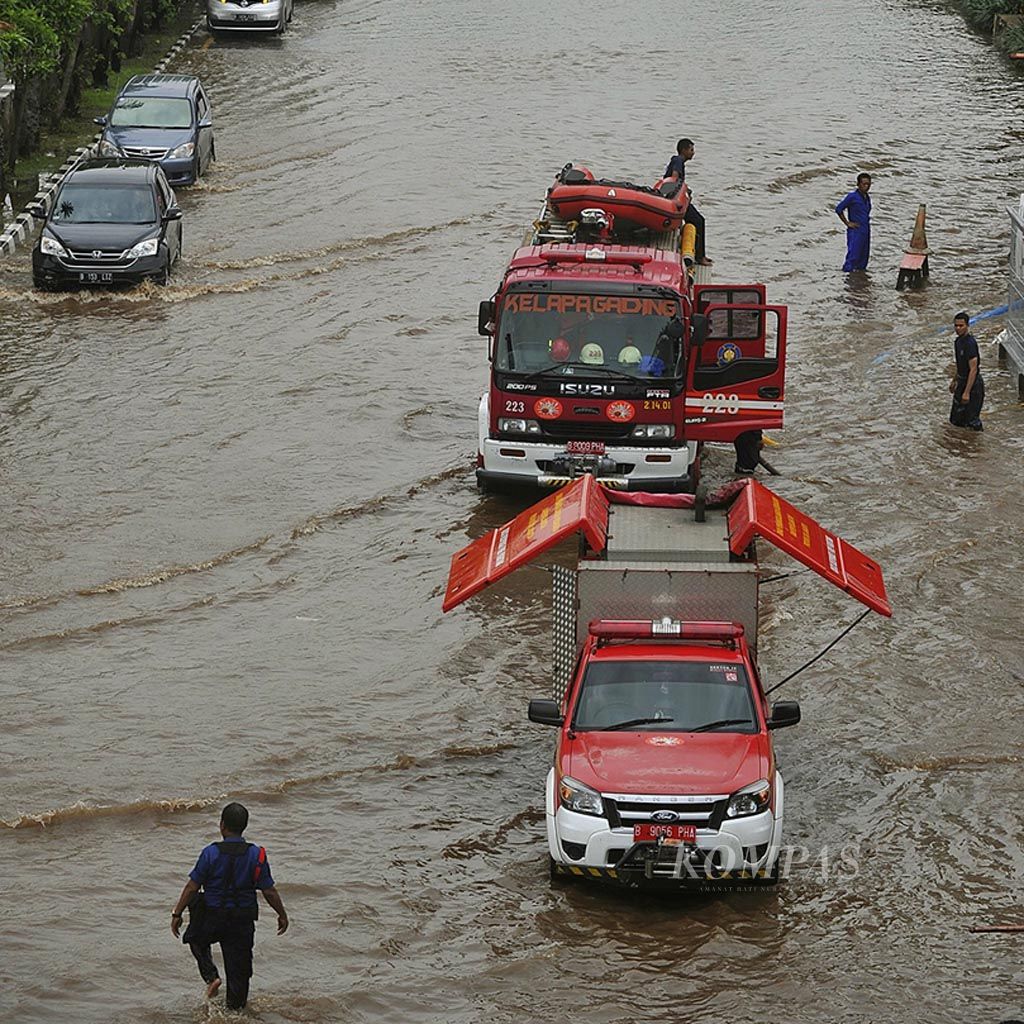 Dua mobil pemadam kebakaran dikerahkan untuk menyedot banjir di Jalan Boulevard Barat, Kelapa Gading, Jakarta Utara, Selasa (21/2). Banjir yang terjadi sejak pagi hari menyebabkan aktivitas perkantoran dan pertokoan di kawasan tersebut terganggu.