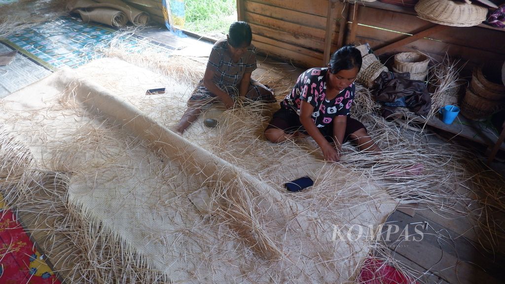 Two women weave rattan mats at a rattan craft center in Pulau Telo Baru Village, Selat District, Kapuas Regency, Central Kalimantan, Monday (15/5/2023).
