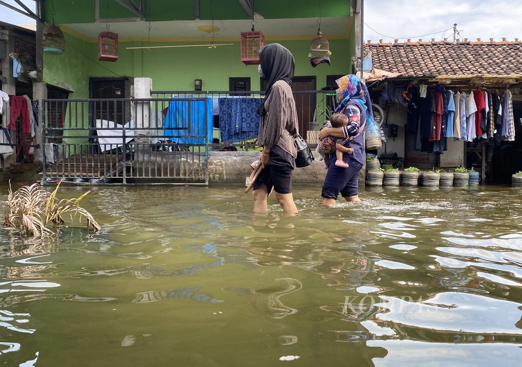 Dua perempuan menerjang banjir yang merendam Desa Sayung, Kecamatan Sayung, Kabupaten Demak, Jawa Tengah, Rabu (10/4/2024). Banjir dengan ketinggian mencapai 60 sentimeter itu terjadi akibat luapan Sungai Dombo-Sayung.