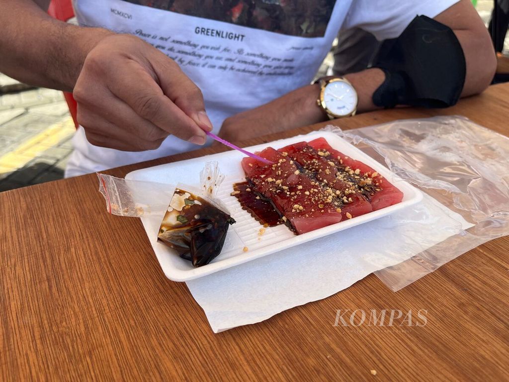 Irisan tuna loin mentah atau sashimi dinikmati seorang pengunjung Festival Tuna Sulawesi Utara di Manado, Sabtu (17/9/2022). 