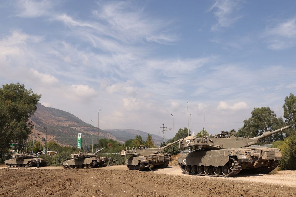 Barisan tank Merkava Israel berkumpul di pinggiran kota utara Kiryat Shmona dekat perbatasan dengan Lebanon, Minggu (8/10/2023). 
