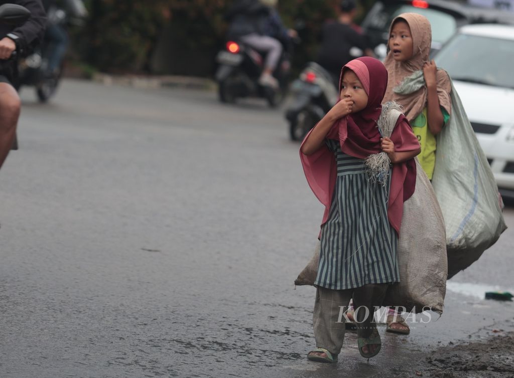 Cahaya (9, kanan) bersama adiknya Fadila (8) berkeliling memulung barang bekas di kawasan Cinere, Depok, Jawa Barat, Senin (26/12/2022). 