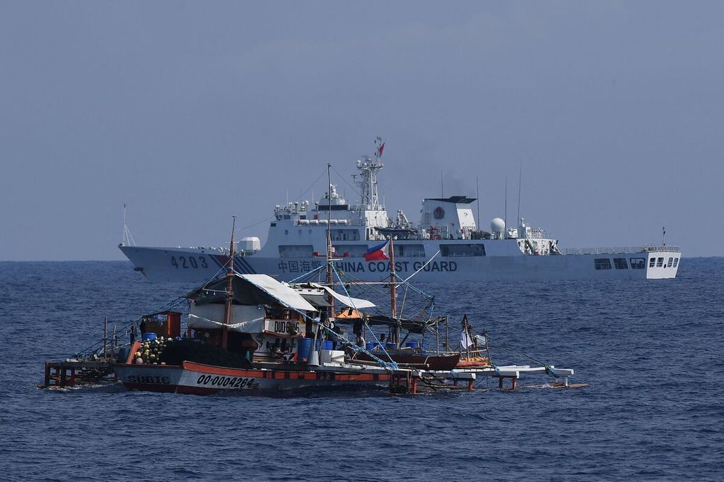 Kapal nelayan Filipina berhadapan dengan kapal Penjaga Pantai China (latar belakang) di Laut China Selatan, 16 Mei 2024.