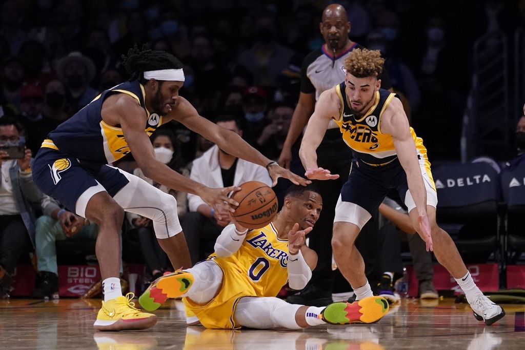 Guard Los Angeles Lakers Russell Westbrook (tengah) melempar bola dari lantai saat dikepung dua pemain Indiana Pacers Isaiah Jackson (kiri) dan Chris Duarte (kanan), pada paruh kedua laga NBA di Los Angeles, Rabu (19/1/2022).