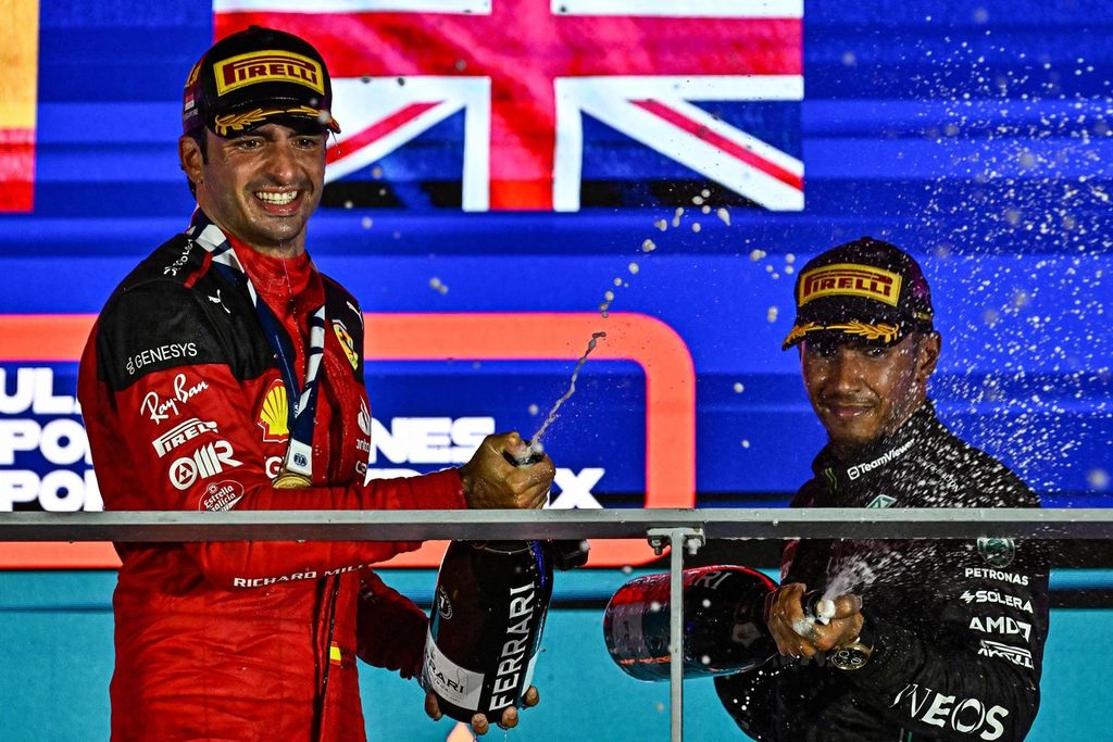 Pebalap Ferrari, Carlos Sainz Jr (kiri), dan pebalap Mercedes, Lewis Hamilton, melakukan selebrasi seusai balapan Formula 1 seri Singapura di Sirkuit Jalan Raya Marina Bay, Singapura, Minggu (17/9/2023). 