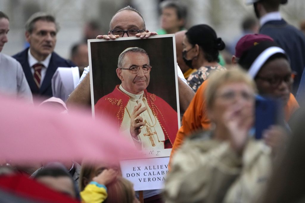 Seorang pria membawa foto Paus Yohanes Paulus I saat misa beatifikasi yang dipimpin Paus Fransiskus di Lapangan Santo Petrus, Vatikan, Minggu (4/9/2022). 