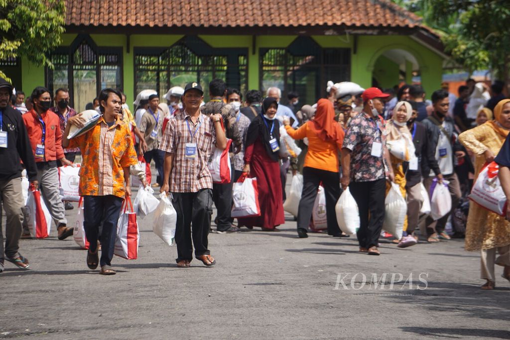 Presiden Joko Widodo mengecek penyaluran bantuan pangan di gudang Bulog Klahang, Sokaraja, Banyumas, Jawa Tengah, Rabu (3/1/2024). Tampak warga penerima bantuan beras dan sembako menggotong bantuan dari negara.