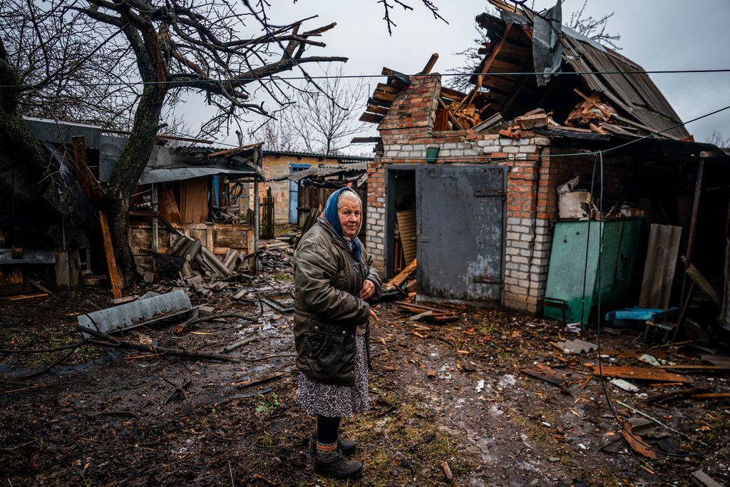 Seorang perempuan tua berdiri di halamah rumahnya setelah serangan udara terjadi di Kota Chasiv Yar, dekat Bakhmut, Ukraina timur, 28 Februari 2023. Militer Ukraina dilaporkan akan melepas Bakhmut. (Photo by Dimitar DILKOFF / AFP)