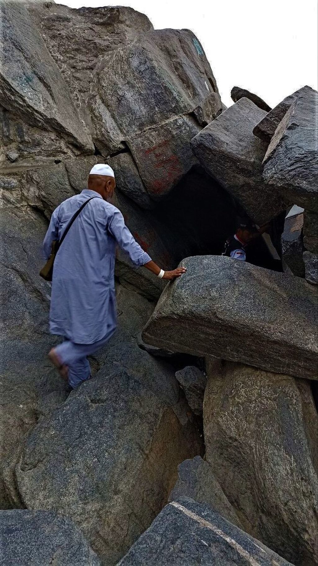 Satu peziarah berada di depan mulut Goa Hira dan satu lagi di dalam ceruk goa di puncak Jabal Nur di Mekkah, Arab Saudi, Senin (1/8/2022) pagi.