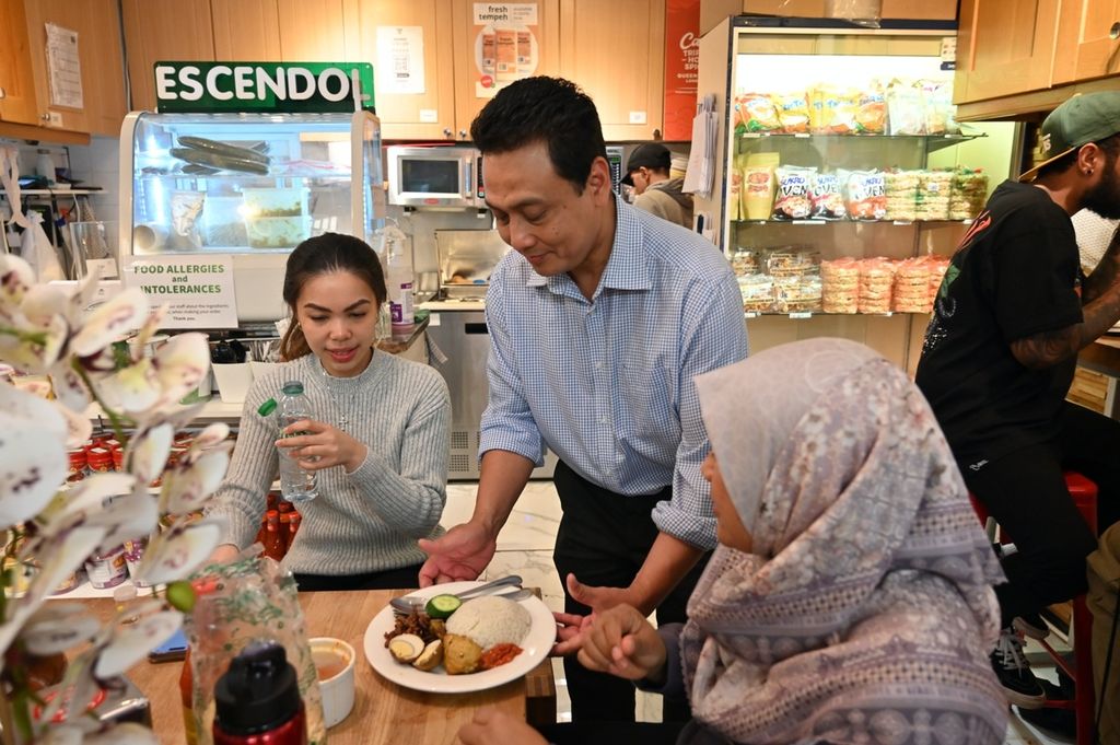 Zukni Legowo (55) menyajikan makanan kepada pelanggan warung makan Triple Hot Spicy di London, Inggris, Rabu (11/10/2023). Zukni tertarik buka warung makan karena sering kangen dengan masakan Indonesia.