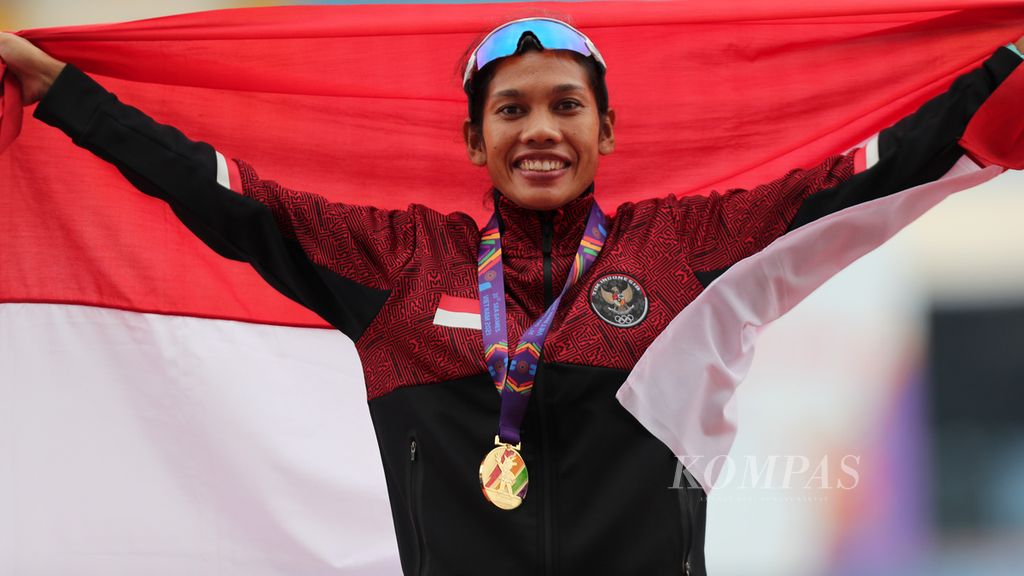 Pelari Indonesia, Odekta Elvina Naibaho, membentangkan bendera Merah Putih seusai pengalungan medali pada nomor maraton SEA Games Vietnam 2021 di Stadion My Dinh, Hanoi, Vietnam, Kamis (19/5/2022). 