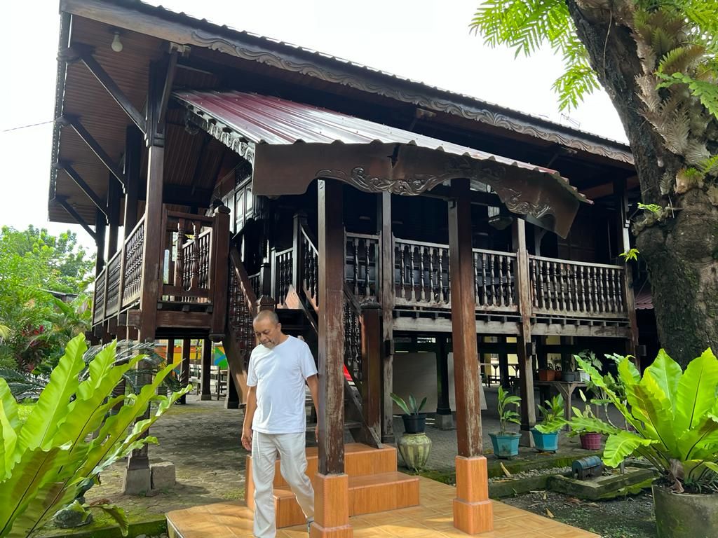 Andi Patahuddin Mallombassang menuruni anak tangga di rumah panggungnya, di Makassar, Sulawesi Selatan, Senin (21/3/2022).