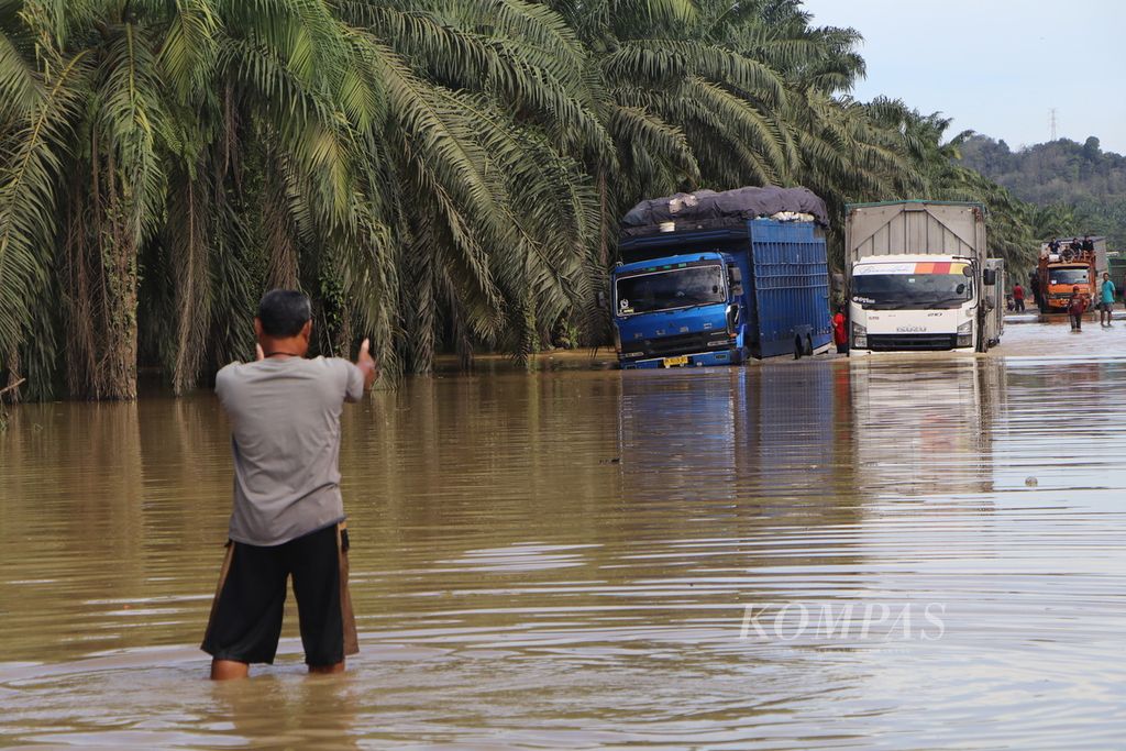 Warga mengarahkan truk dan bus untuk melewati genangan banjir di Jalan Medan-Banda Aceh di Kecamatan Kejuruan Muda, Kabupaten Aceh Tamiang, Aceh, Minggu (6/11/2022). 